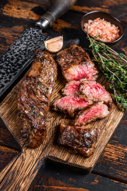 Grilled bbq skirt steaks slices on a wooden board. Dark wooden b